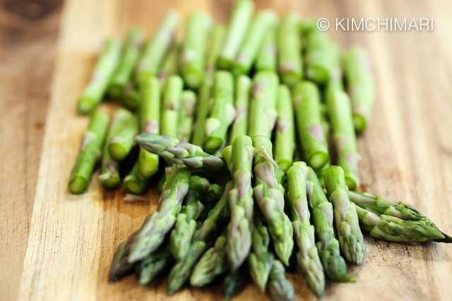 asparagus cut into 3rds on wooden cutting board