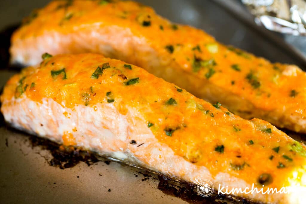 baked salmon covered in mayo sauce on sheet pan