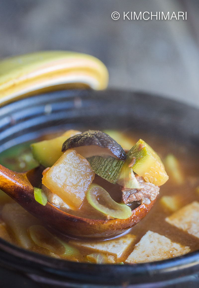 Doenjang Jjigae in a ladle over steaming pot