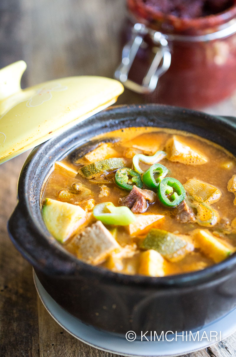 doenjang jjigae in stone pot with gochuang jar in the background