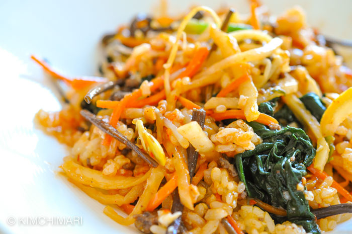 rice meat and vegetables mixed with sauce in a white bowl