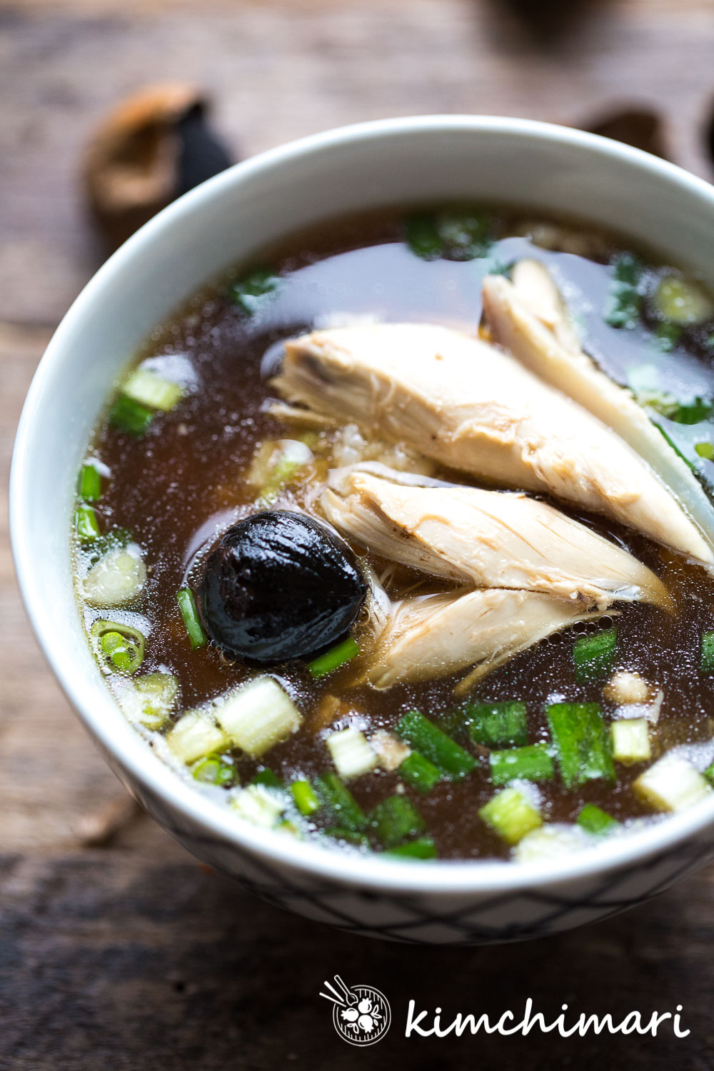 Korean Chicken soup with torn meats in bowl with Black Garlic and green onions