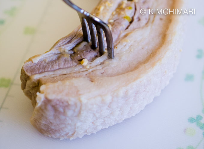 boiled pork belly with fork in it on cutting board