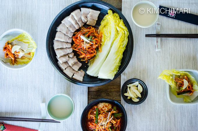 Table setting top view for two with bossam in the middle and makgeolli in cups with chopsticks