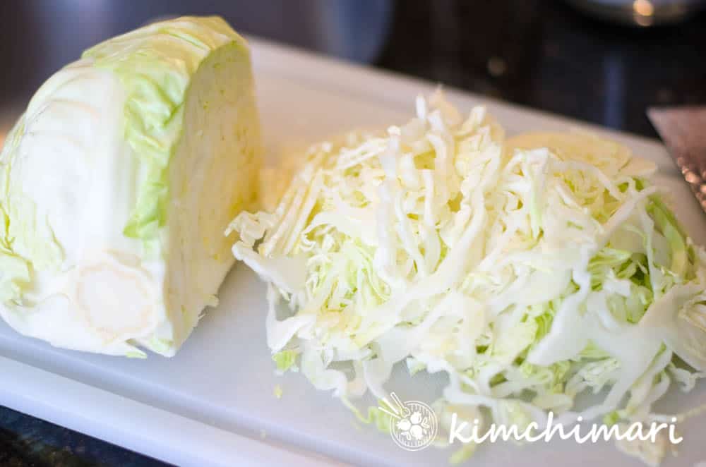 green cabbage on cutting board sliced thinly