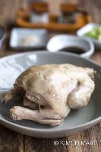 cooked whole chicken on plate with sauces in the background