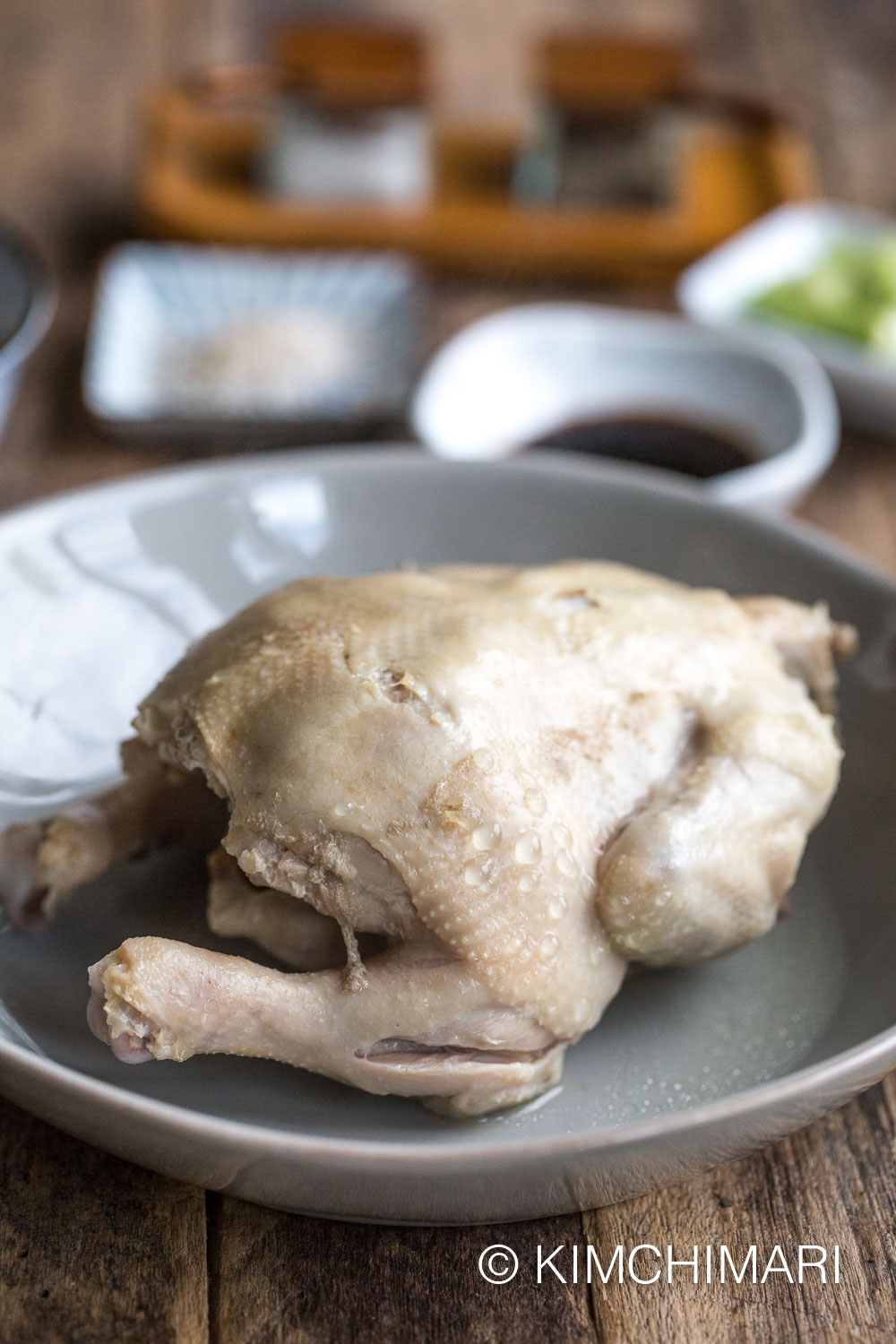 cooked whole chicken on plate with sauces in the background