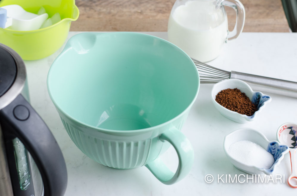 ice, mixing bowl, milk, coffee, sugar and whisk laid out on table