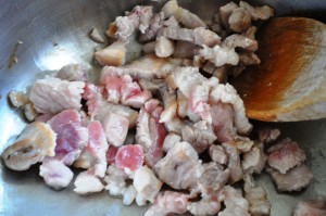 sauteeing pork in stainless pot with wooden spatula