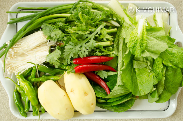 Veg ingredients of green onions, potatoes, chili peppers, perilla leaves laid out on tray