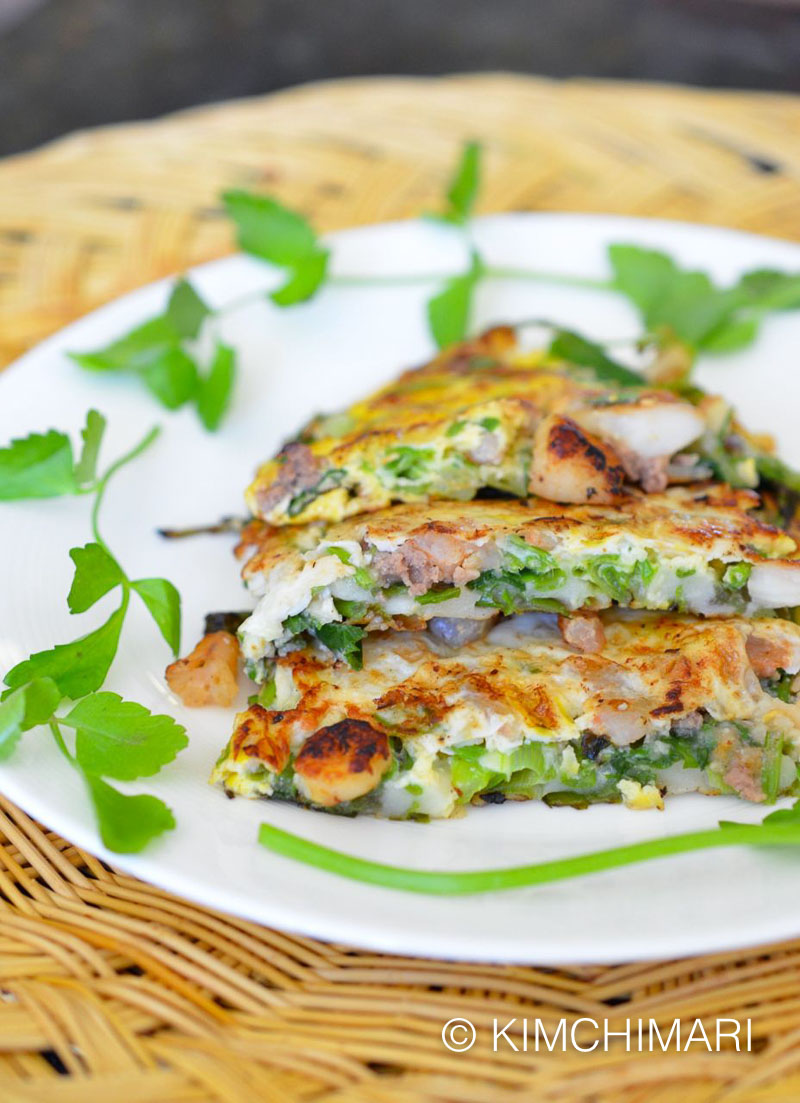 pajeon pancake plated on white dish on bamboo mat