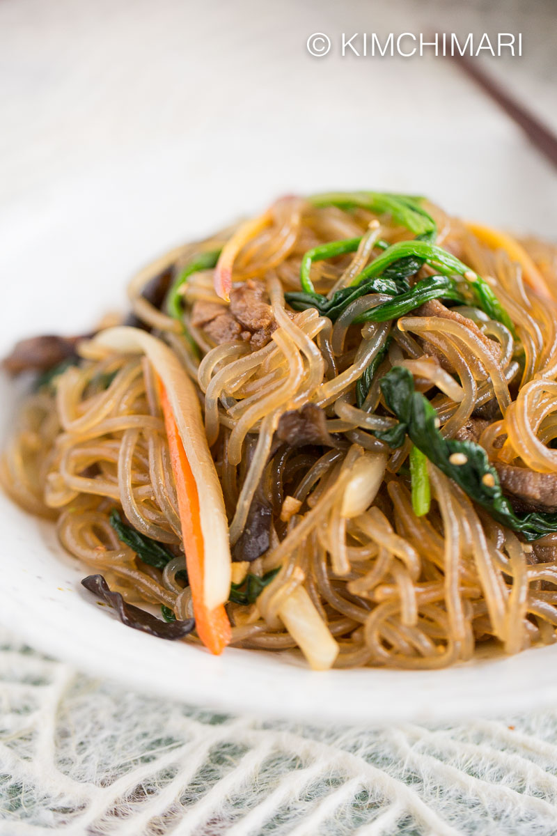 Close up of Japchae with beef and vegetables plated on white plate