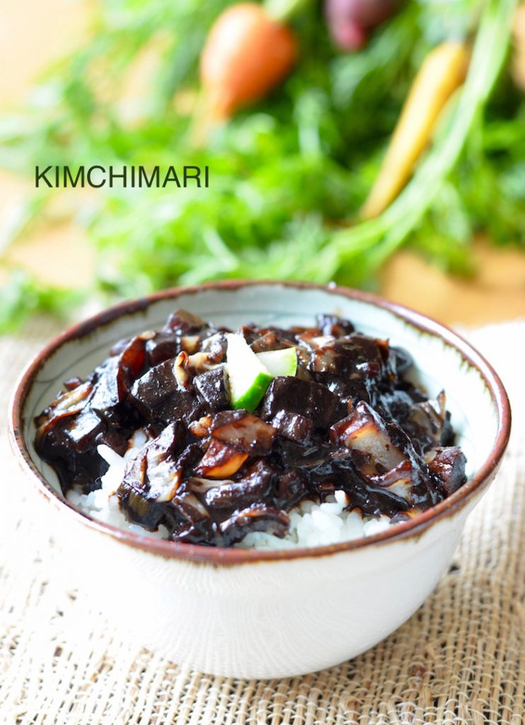 bow of rice topped with jajang sauce with carrots in the background