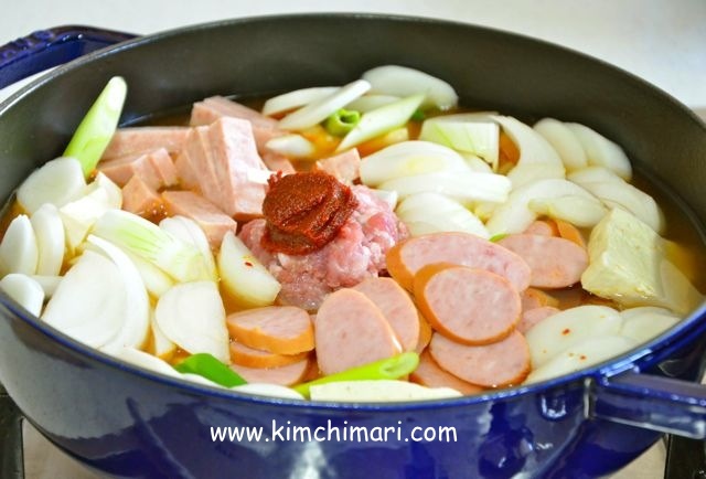 Budae Jjigae with all ingredients in pot with water added