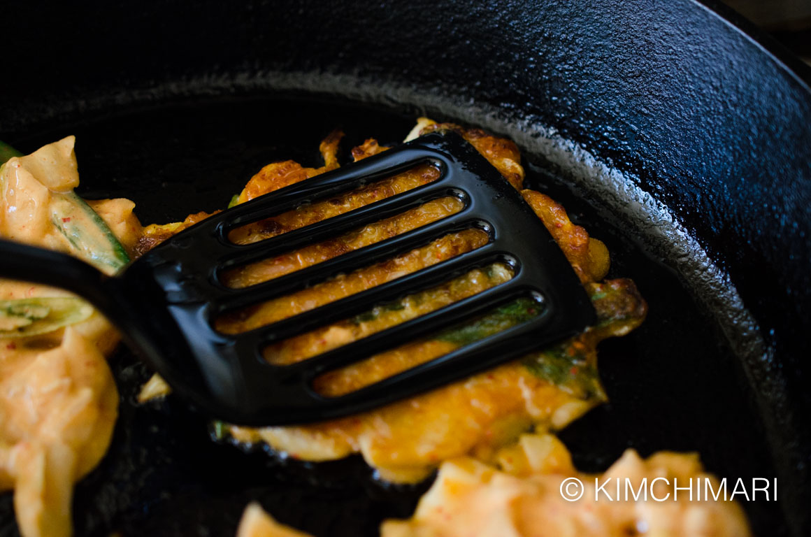 Pressing kimchi pancake buchiimgae with turner