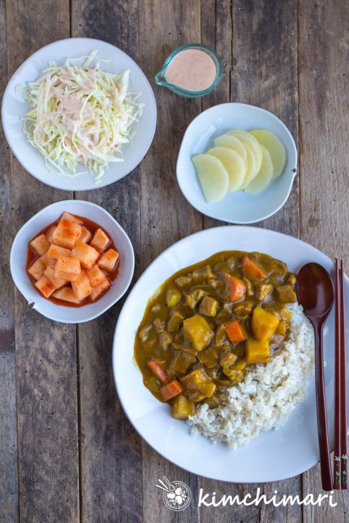 top view of korean curry rice served with side dishes of kkakdugi, danmuji and cabbage salad