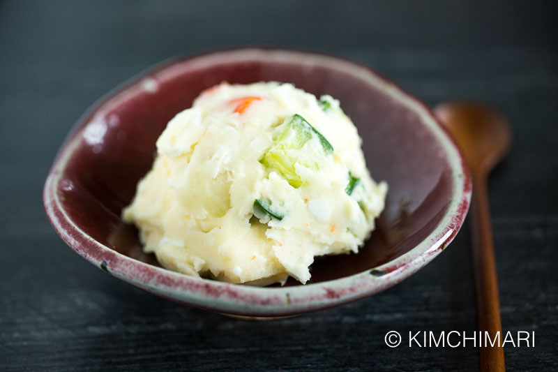 potato salad served as a scoop using ice scream scooper on red ceramic bowl