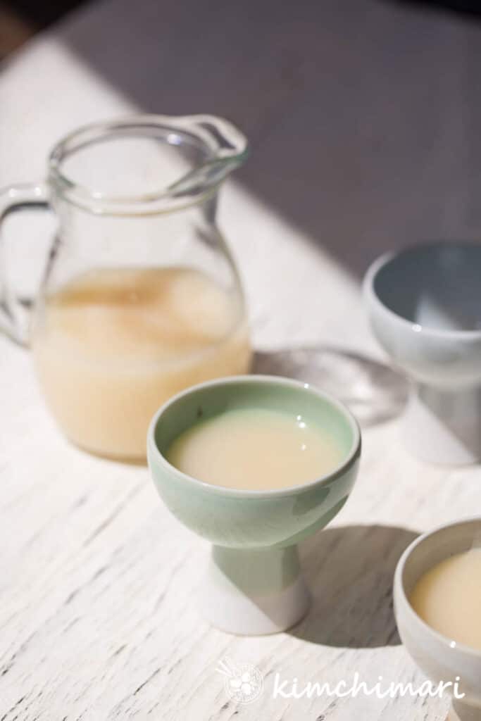 makgeolli in a glass pitcher and couple glasses with sun shining on it