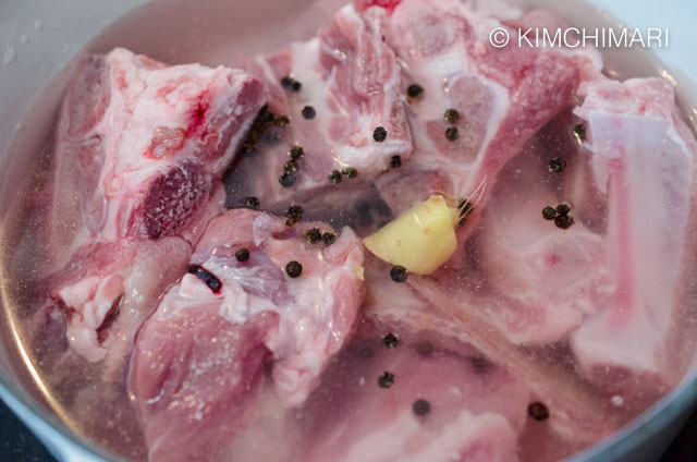 pork neck bones in pot with water, pepper corns, ginger