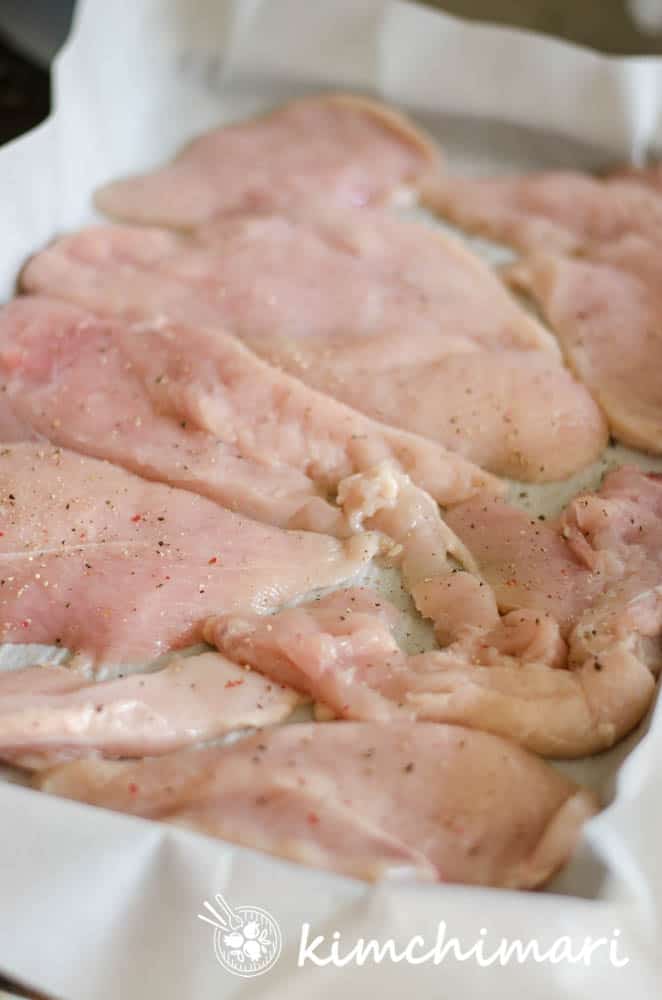 salt and peppered chicken breast slices on tray