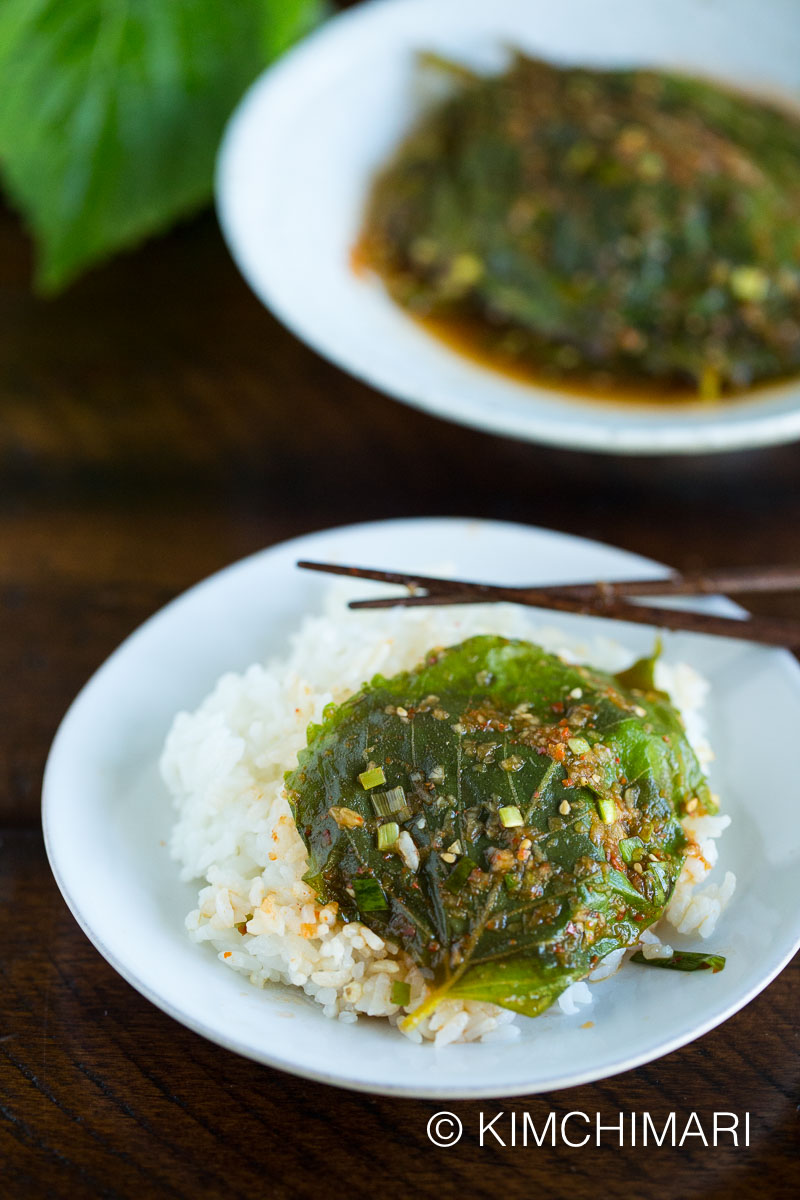 steamed perilla leaves laid out on a bowl of rice with chopsticks