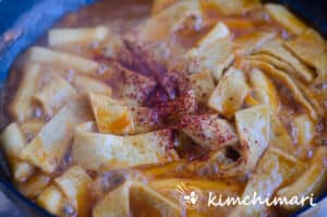 tteokbokki bubbling in pan with Gochugaru sprinkled