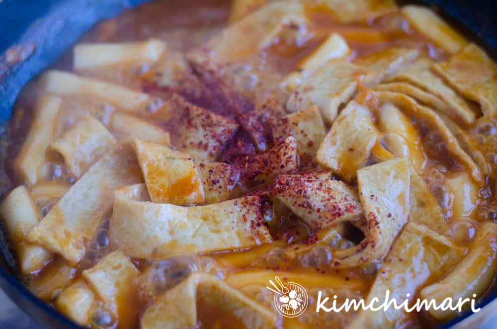 tteokbokki bubbling in pan with Gochugaru sprinkled