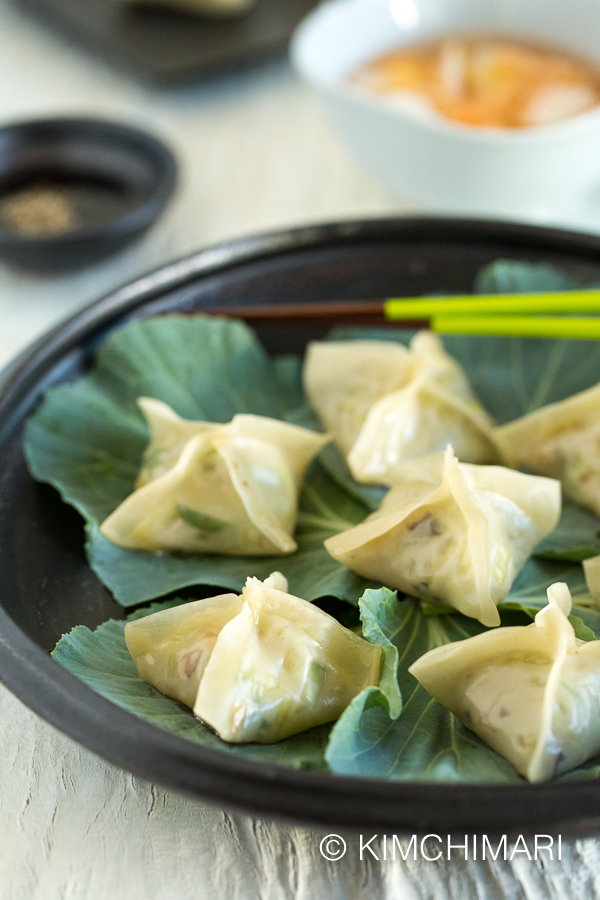 vegetarian dumplings served on black plate with dipping sauce in the background