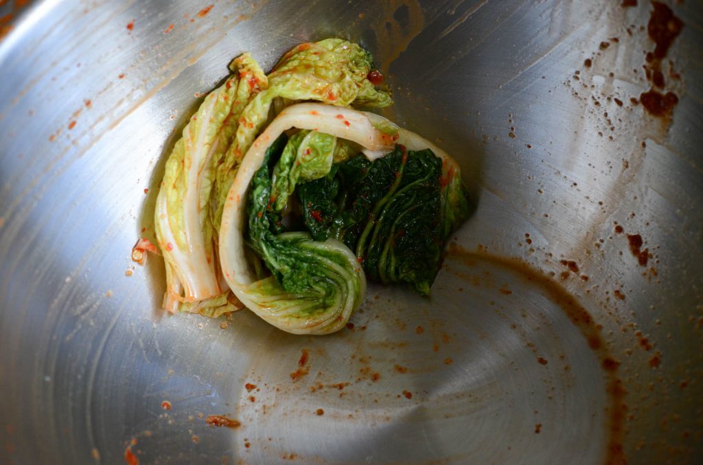 Wiping kimchi mixing bowl with cabbage leaves